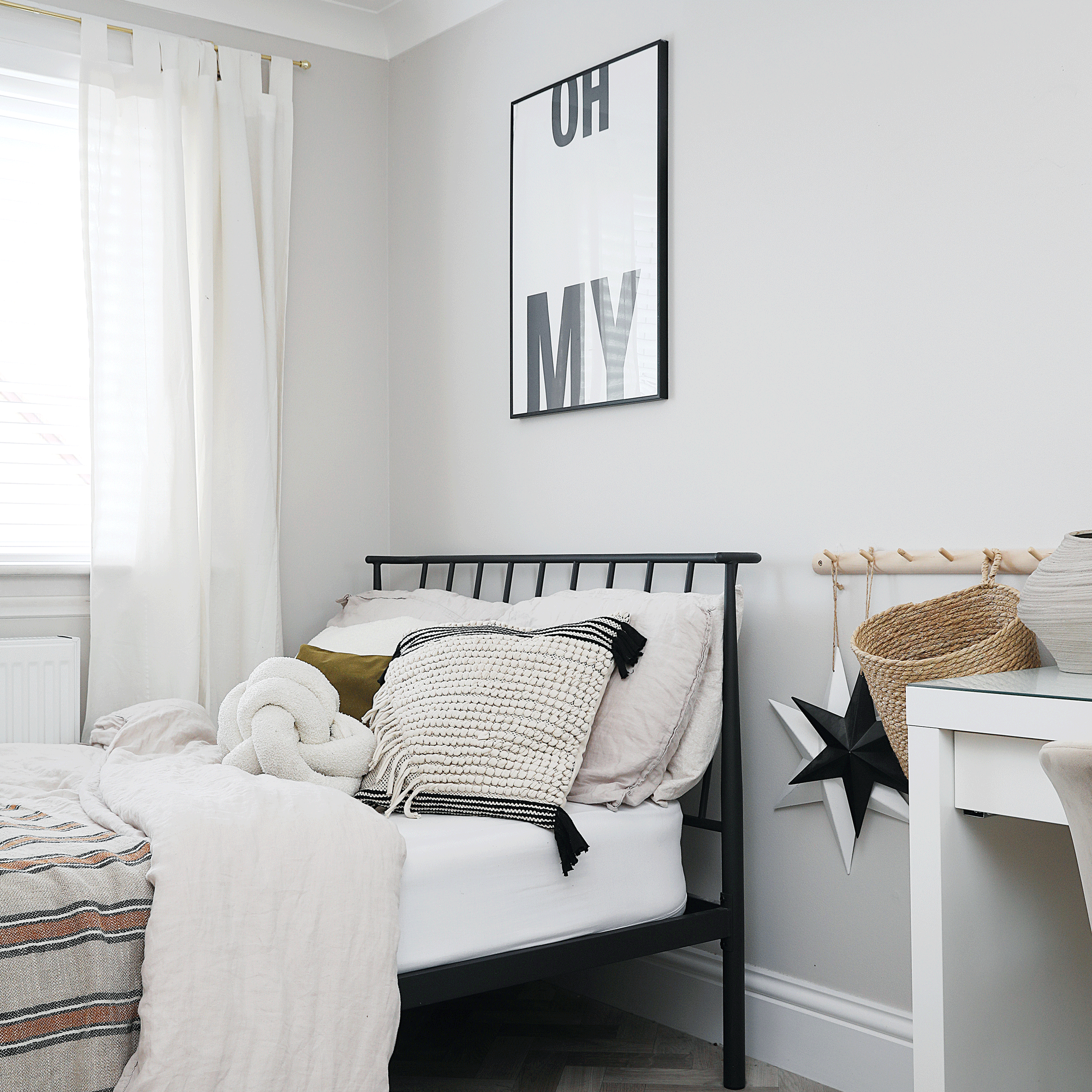 a monochrome bedroom with a black bedframe wooden peg rail black and white typography art