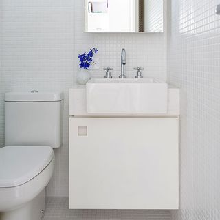 Bathroom with white washbasin and white tiled walls