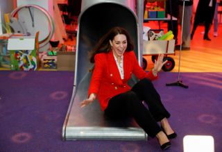 Catherine, Duchess of Cambridge reacts as she slides down a slide during a visit at the LEGO Foundation PlayLab