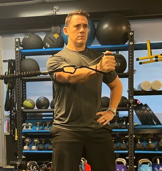 Man doing single arm resistance band pec fly