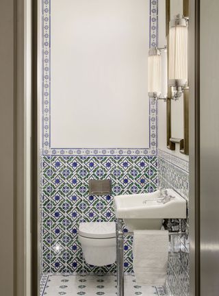 Powder room with blue and white tiles and pendant lights on either side of a mirror