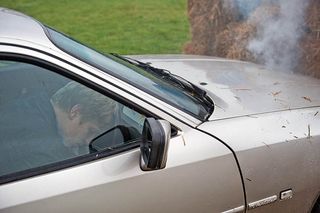 Robert lies motionless at the steering wheel, as smoke begins to billow from the front of his car...