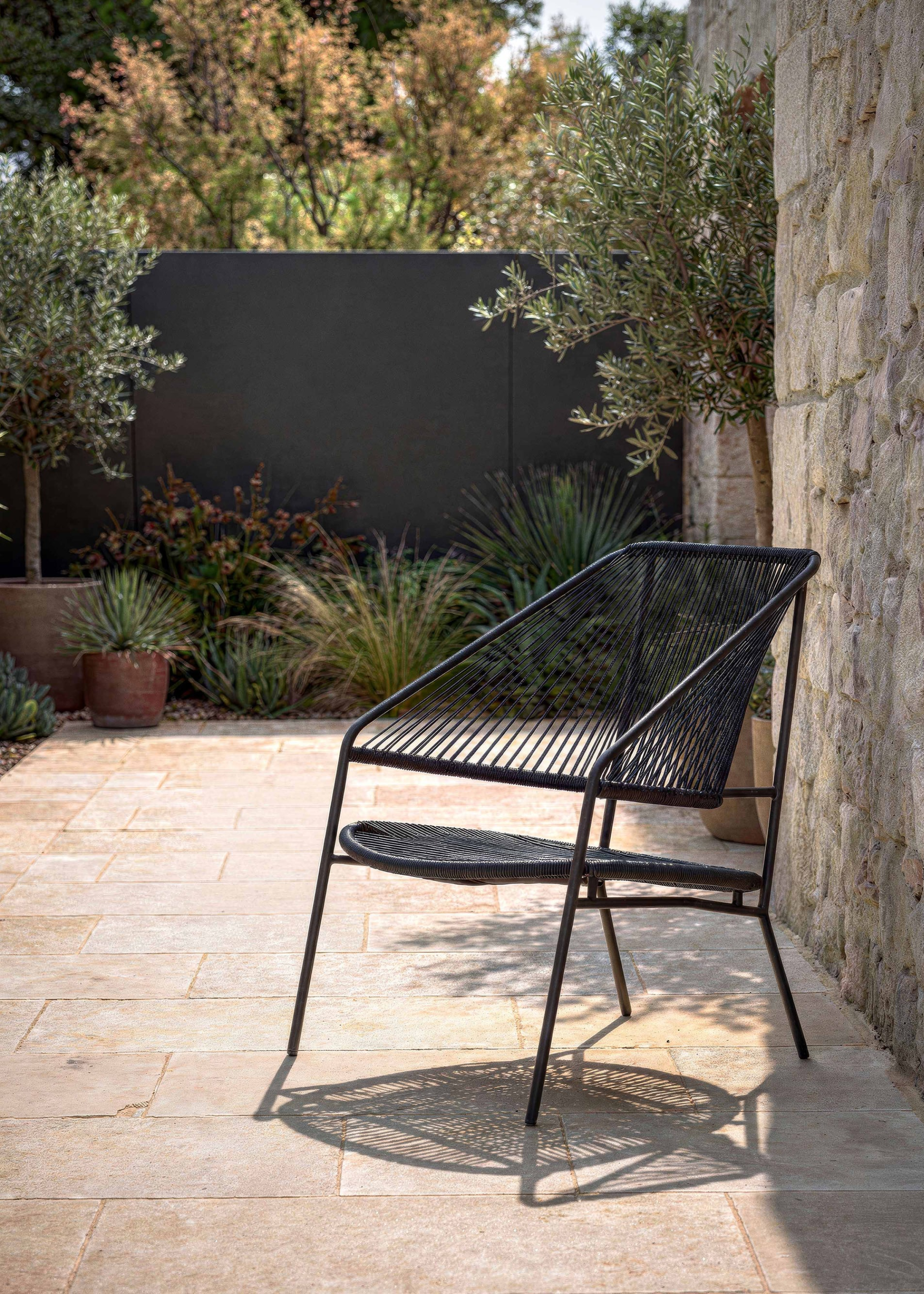 A rope black chair from Westwing in a backyard