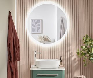 pink and green bathroom with large circular mirror with lights