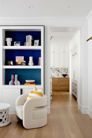 display shelving by doorway to white kitchen with marble splashback
