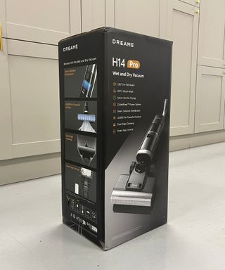 Black Dreame H14 Pro cardboard box with graphics of the cordless vacuum and text listing its key features in front of gray cabinets in Future test center