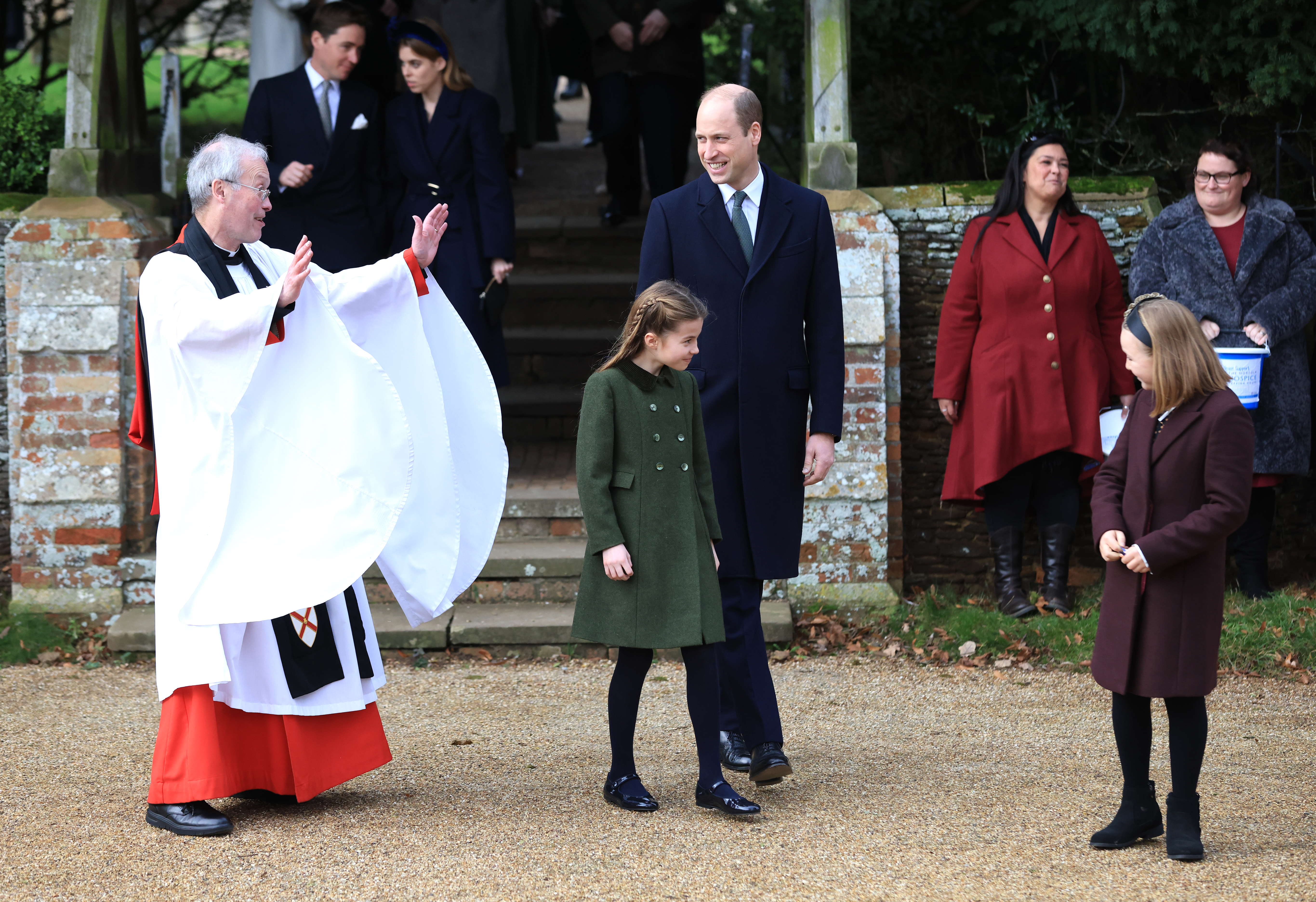Princess Charlotte smirking at Mia Tindall with Prince William and a vicar standing behind them