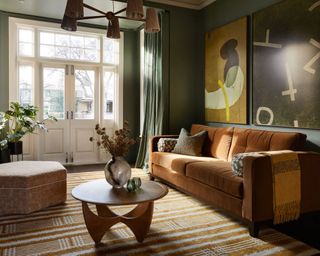 living room with dark green walls, burnt orange sofa and dark yellow accessories