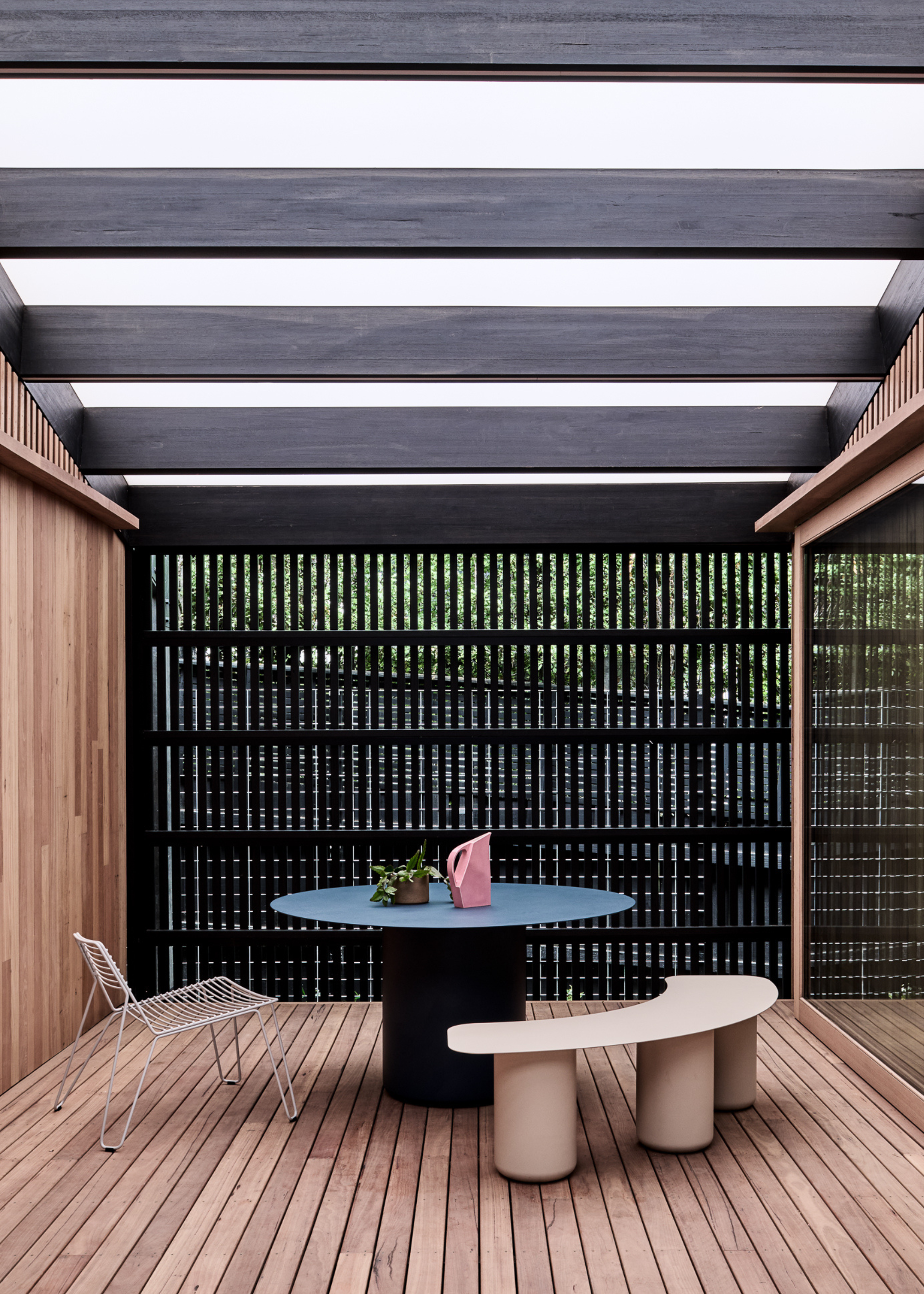 An outdoor-indoor space with a round table, a curved bench and a metal chair