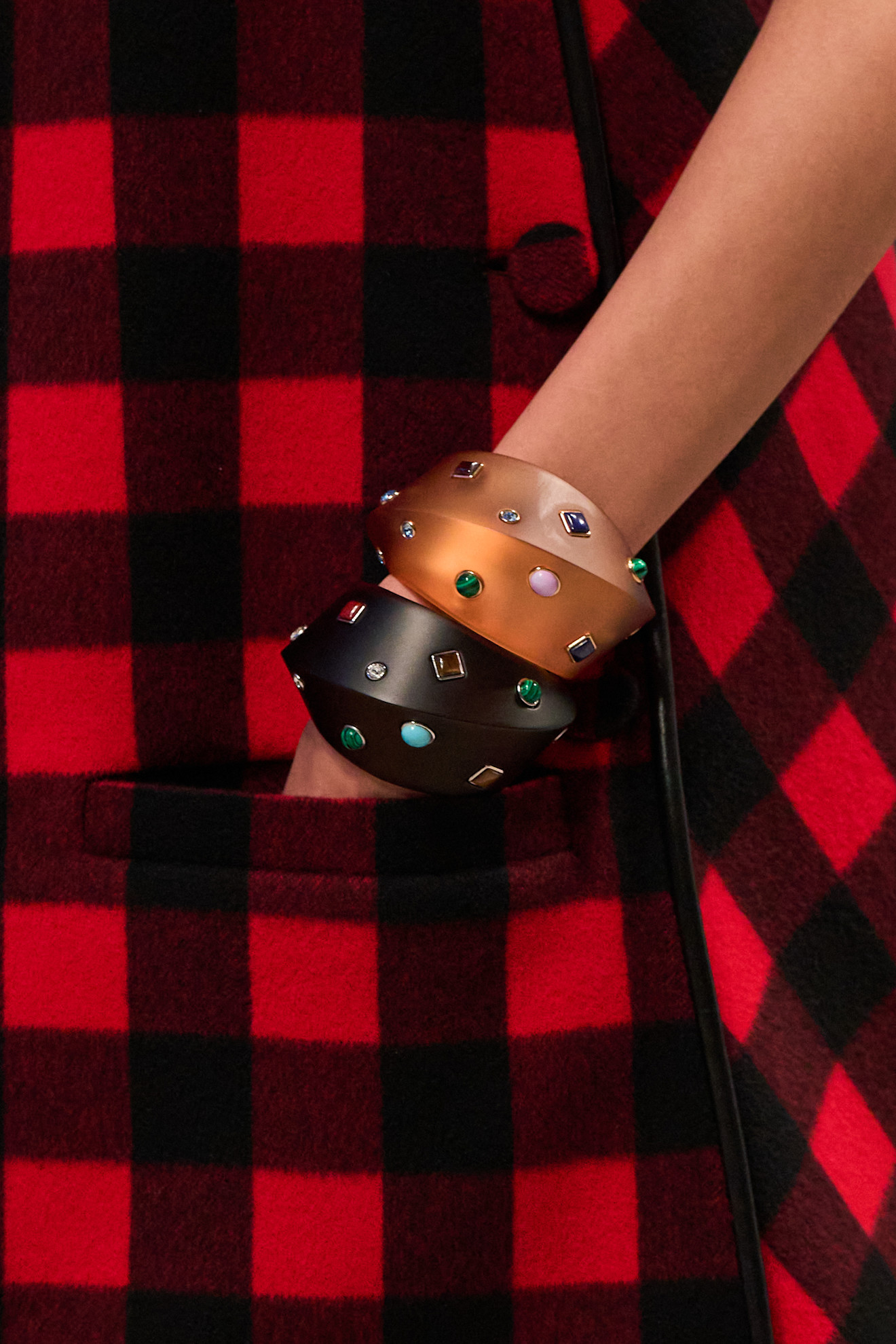 A Louis Vuitton model wearing colorful gemstone stacked bangles.