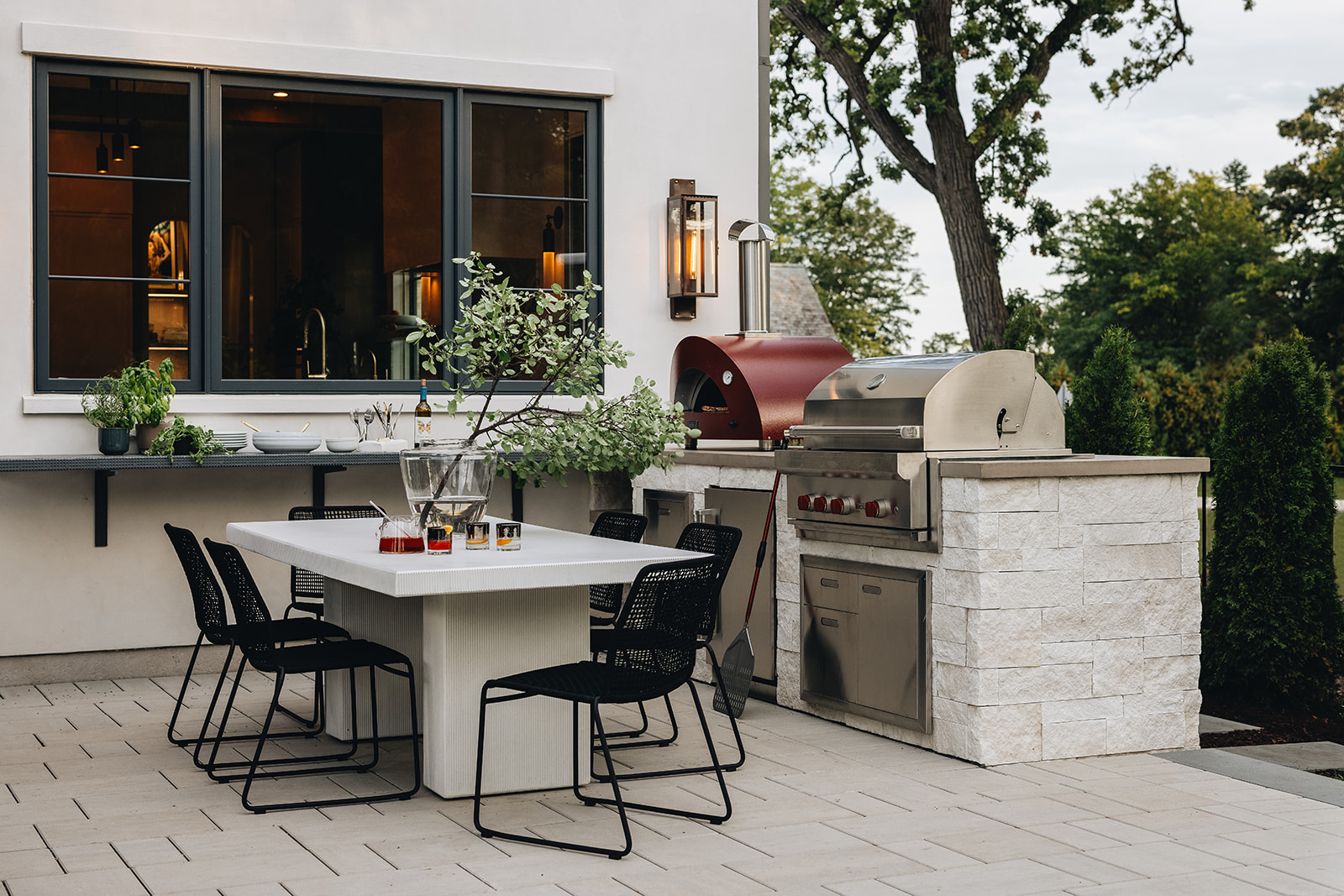 An outdoor seating, with an outdoor dining, and a built in grill that also has a pizza oven placed next to it