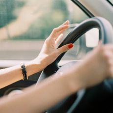 A woman's hands on a car steering wheel.