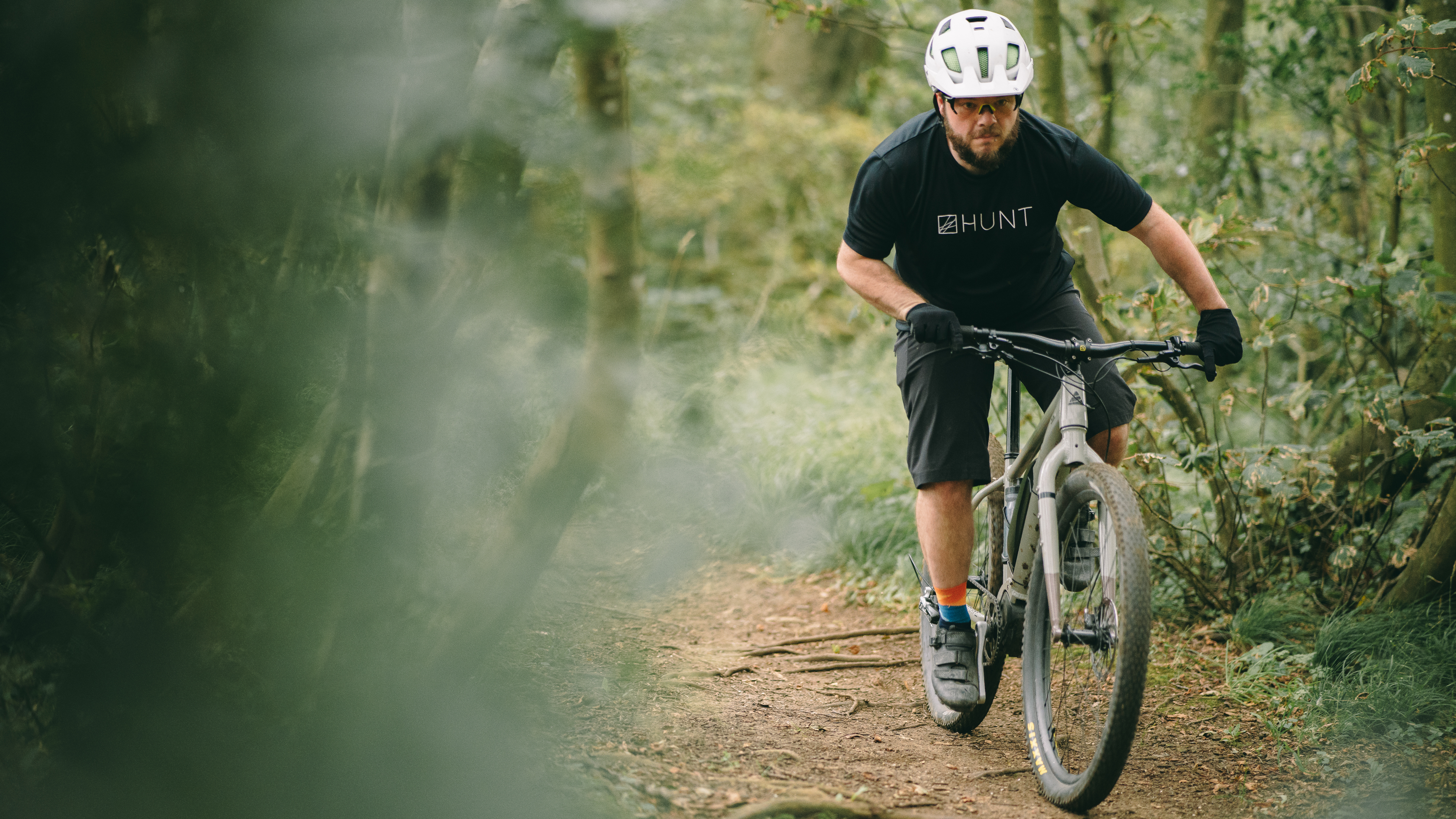 Tech Writer Matt riding a prototype Cairn Brave electric gravel bike in some woods.