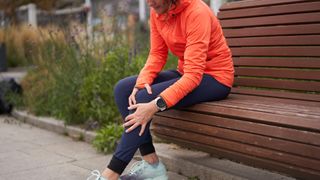 Knee strengthening exercises: Woman sat on bench mid-exercise holding her knee 
