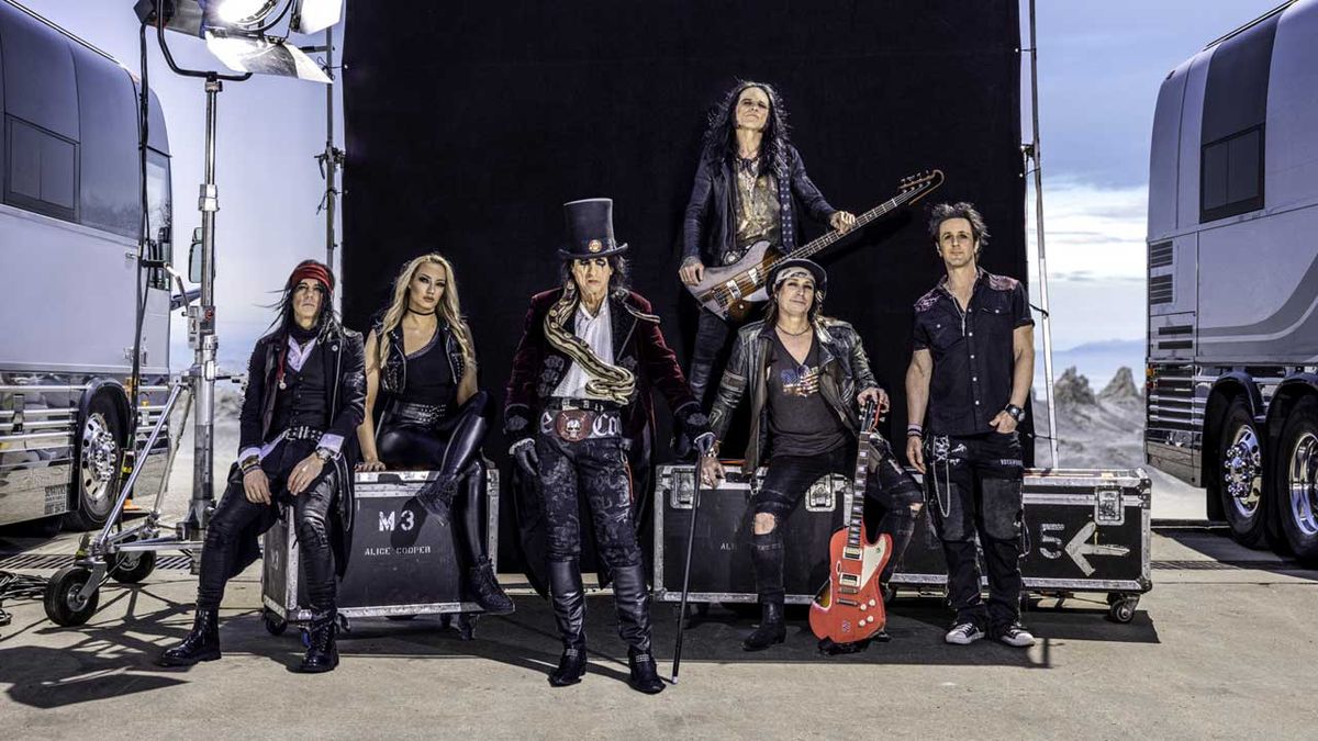 Alice Cooper and band posed beside two tour buses and some flightcases 