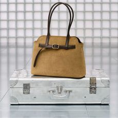 Charles & Keith suede handbag on silver briefcase with white grid wall