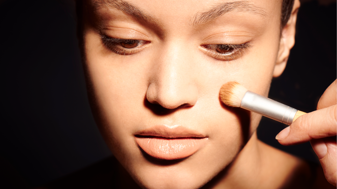 Woman applying powder makeup with brush 