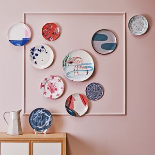 Pink wall with mismatched plates as decor