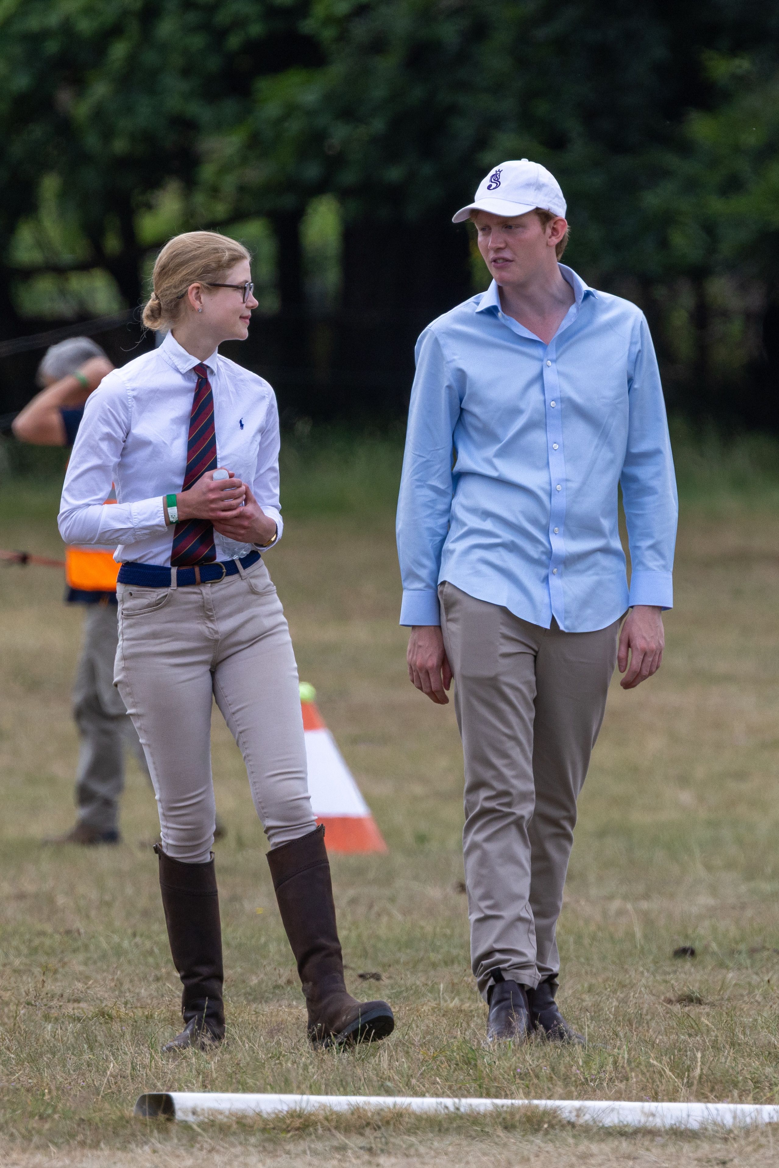 Lady Louise Windsor wearing a striped tie and khakis smiling at her boyfriend Felix da Silva-Clamp in a field