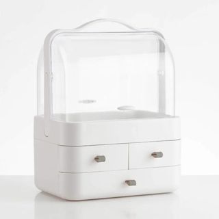 A white makeup organizer box features drawers at the bottom, and a clear compartment at the top