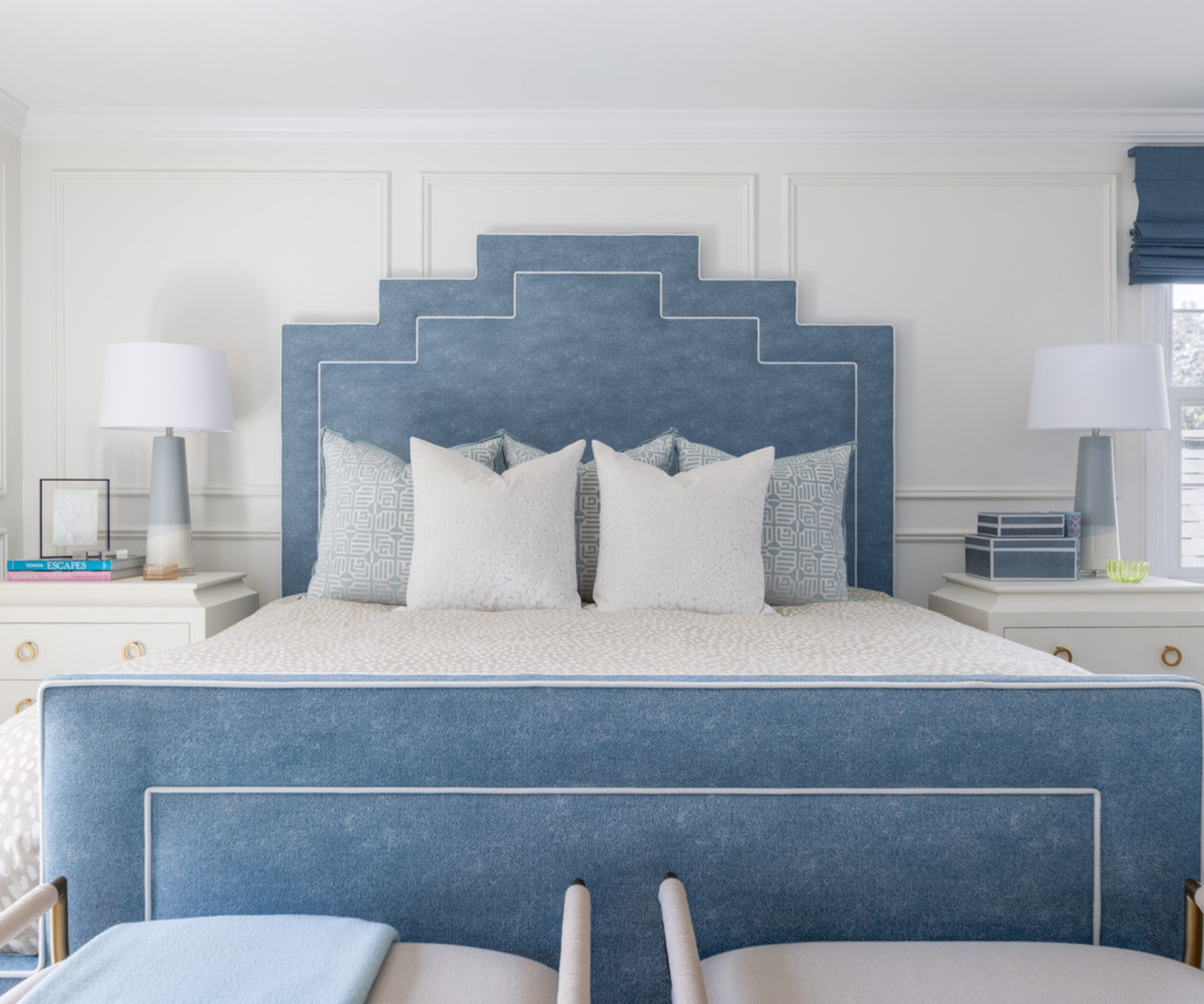 a bedroom with a large blue bedframe, pillows on the bed, and symmetrical nightstands on either side