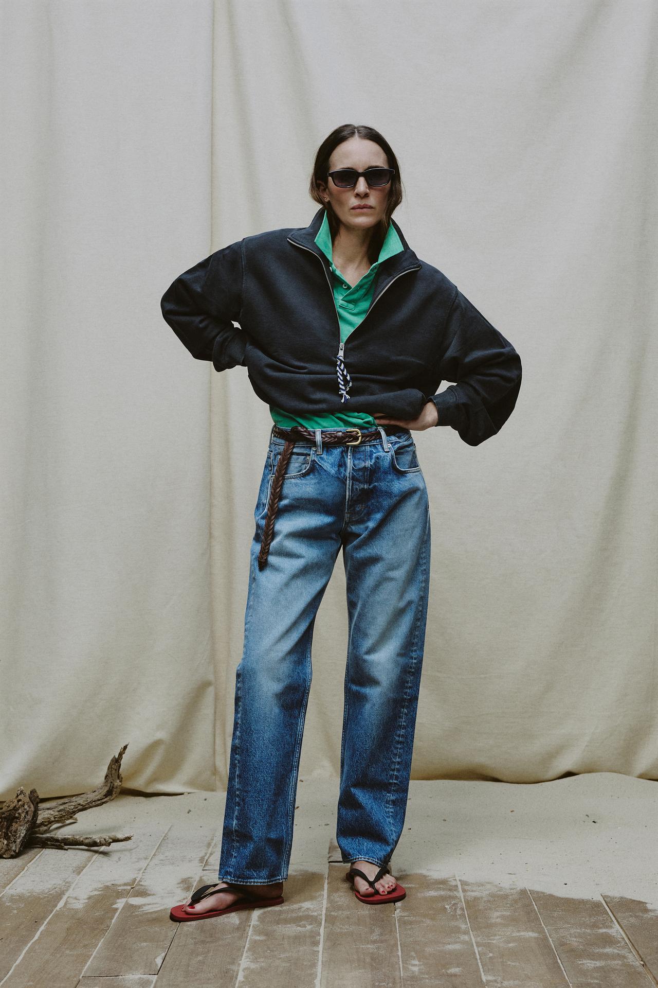 Model wears jeans, flip flops, quarter zip, and green polo shirt.