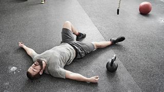 Man lies on gym floor after working out