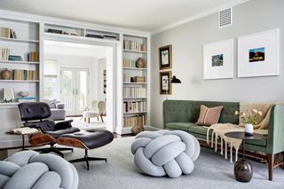 white walls living room with green sofa, eames chair and fitted bookcase