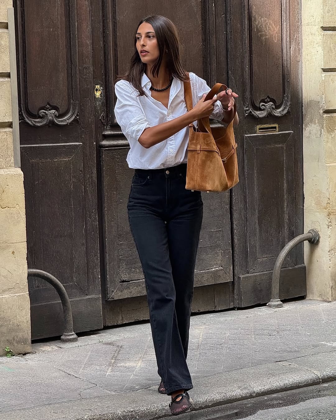 Salom&amp;eacute; Mory wearing a white button-down with jeans and a brown suede bag.