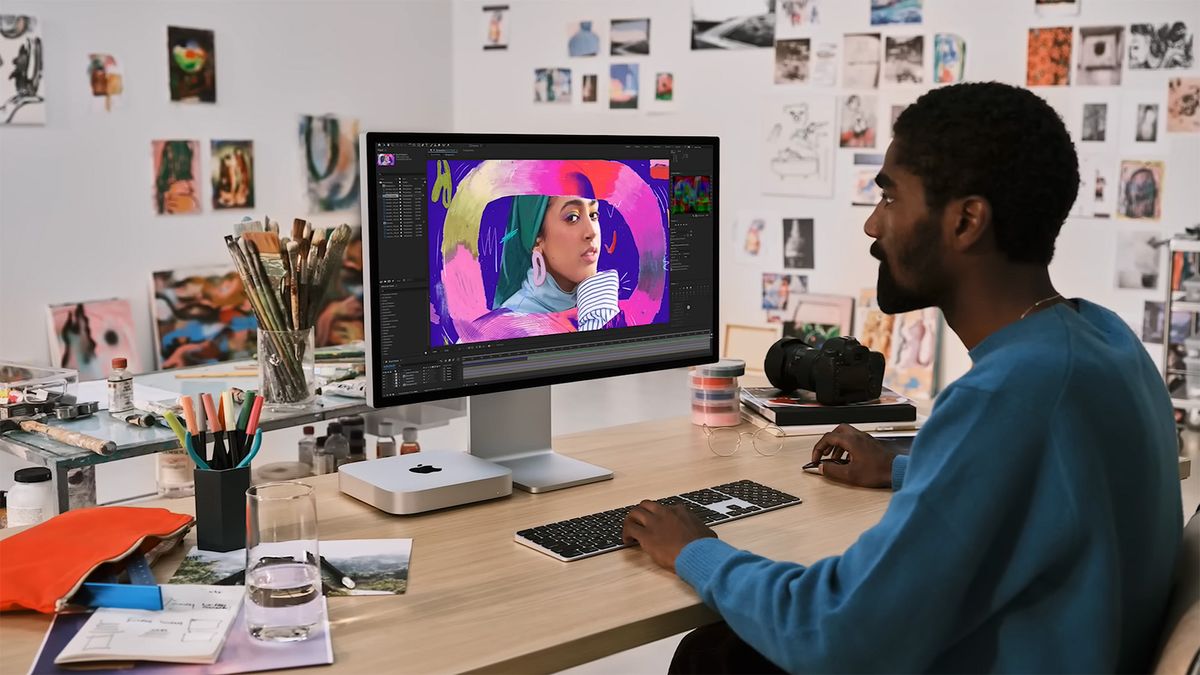 A man sitting at a desk editing a photo on an M2 Mac mini