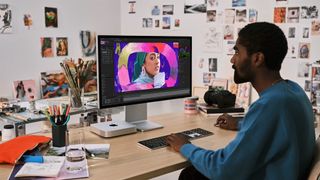 A man sitting at a desk editing a photo on an M2 Mac mini