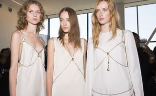 models wearing white out fit with golden chain design