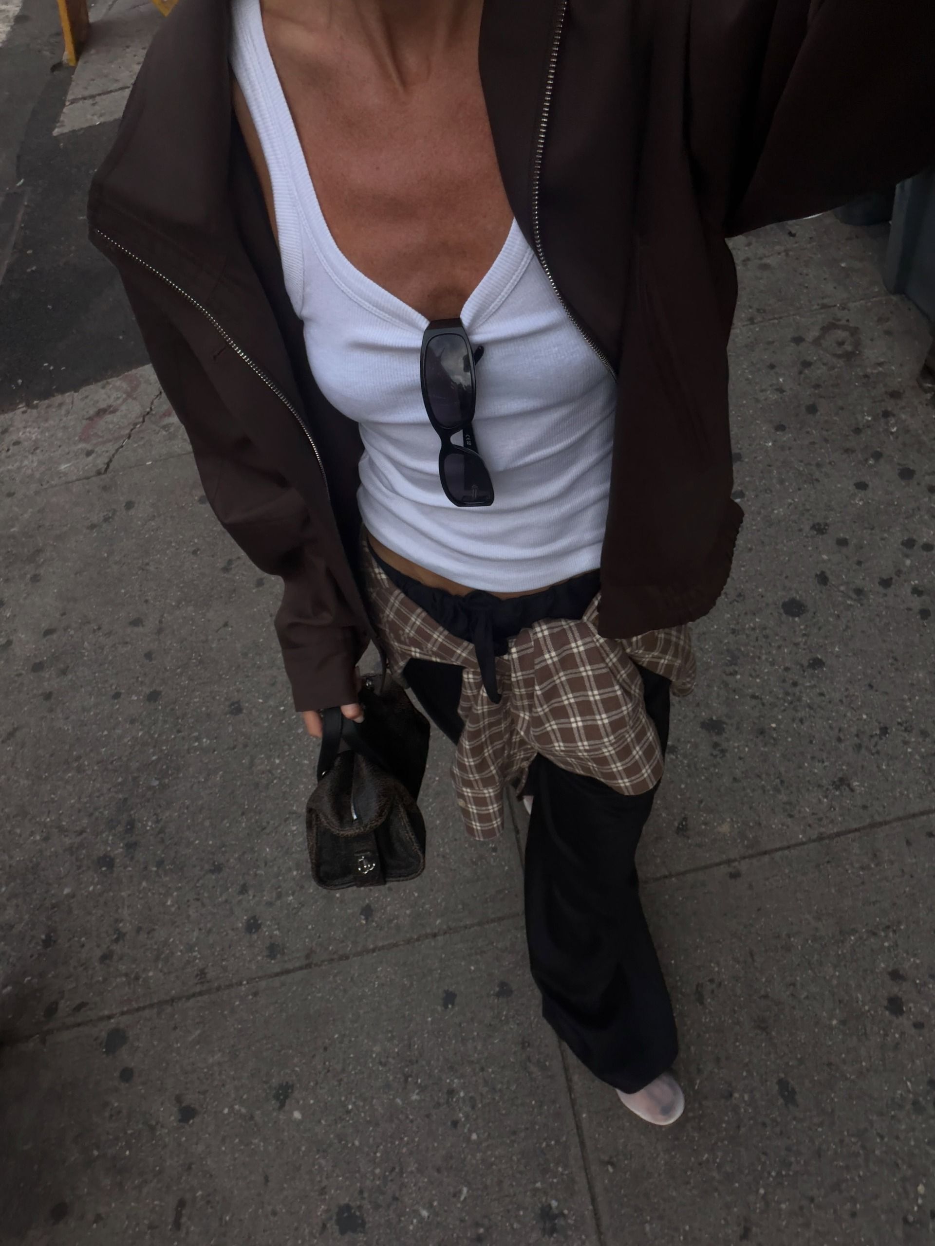 Woman wears jacket, white tank, black trouses and check shirt