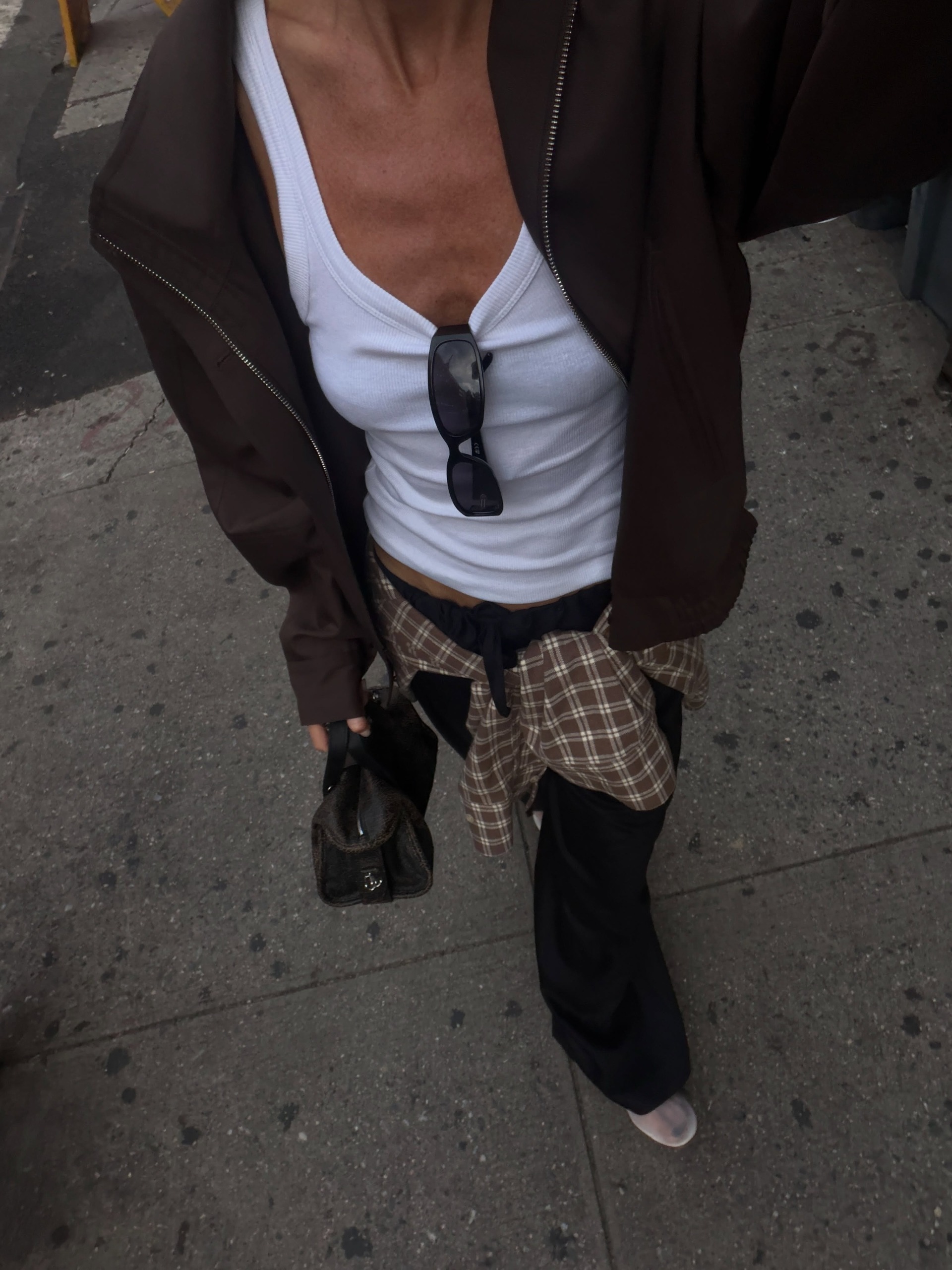 Woman wears jacket, white tank, black trouses and check shirt