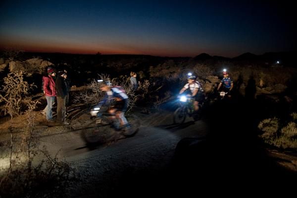 Heading towards the finish of the first night lap at the Kona Bikes 24 Hours in the Old Pueblo, a group of riders bask in the glow of headlamps and the setting sun.