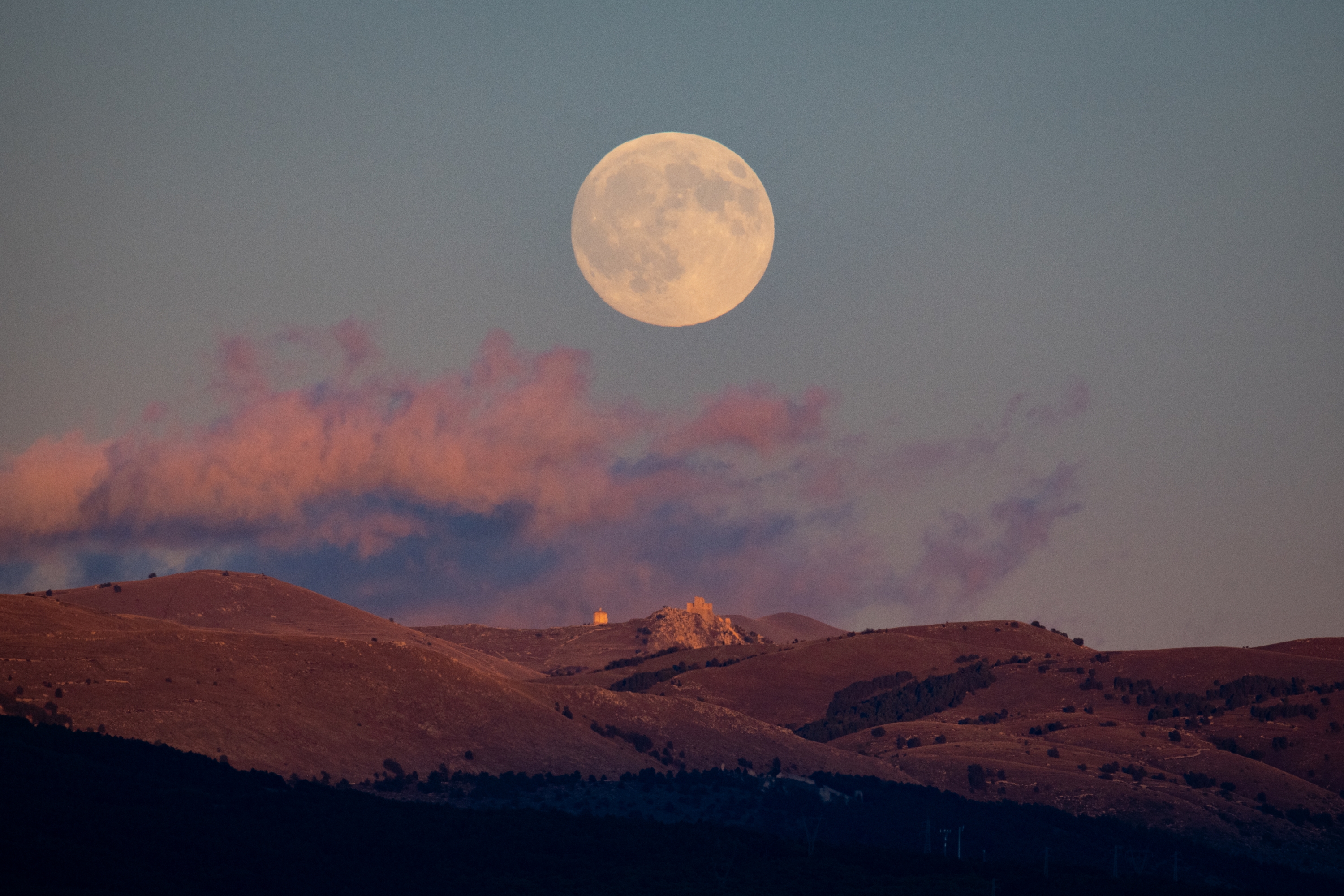 A photograph of the Harvest supermoon rising above Rocca Calascio Castle and Santa Maria della Piet&amp;agrave; church in Calascio, Italy.
