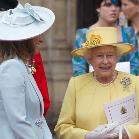 Carole Middleton wearing a blue hat and coat talking to Queen Elizabeth at William and Kate's wedding