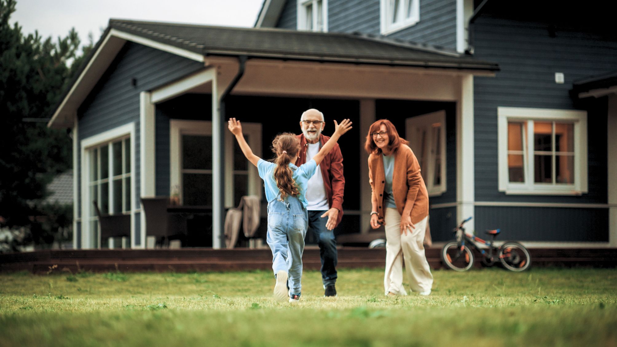 A grandchild running across the lawn to greet her grandma and grandpa. 