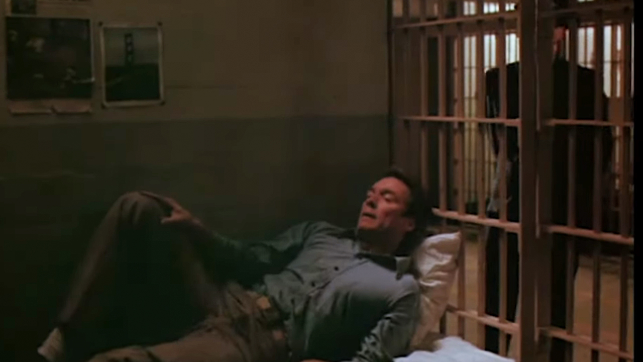 Clint Eastwood lying in bed in a jail cell.