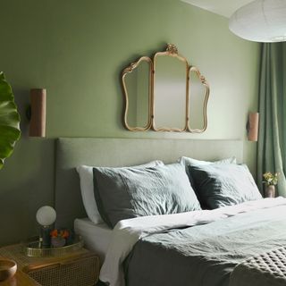 A bedroom with an earthy green wall paint