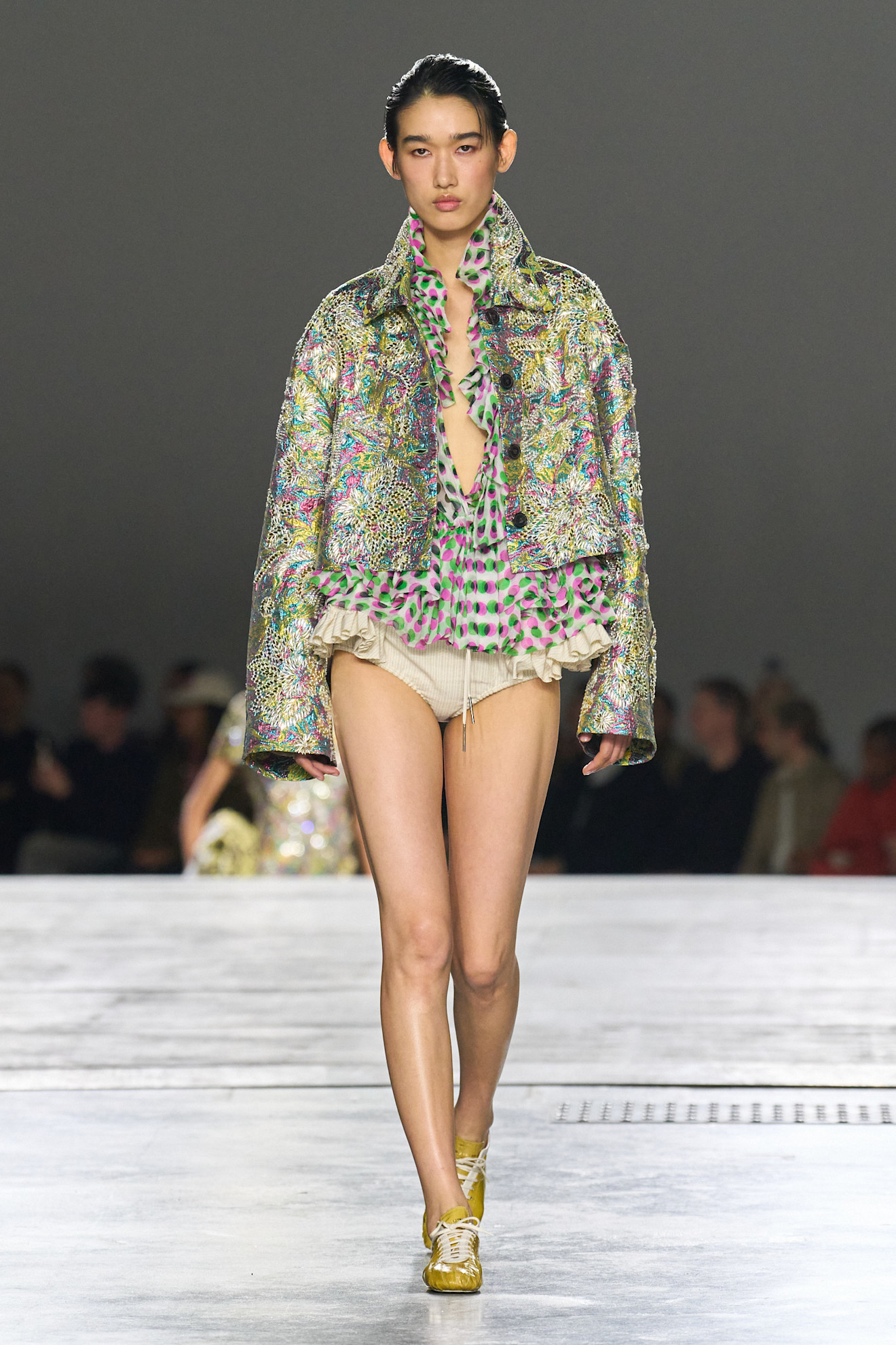 A model at the spring/summer 2026 Dries Van Noten show wearing a beaded, multicolor jacket with a polka dot printed blouse.