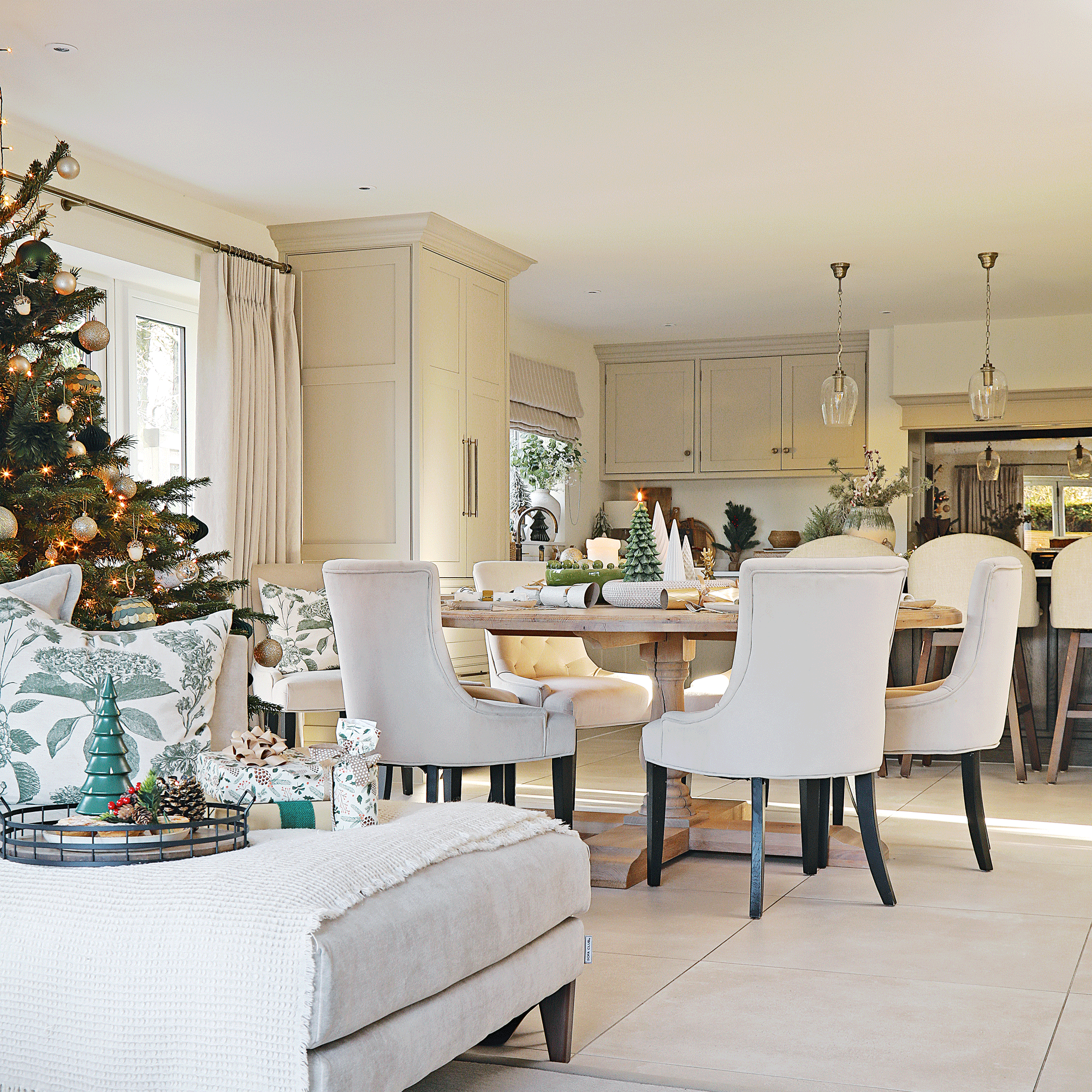 a neutral open plan kitchen/living/dining room with a christmas tree and corner sofa with lots of festive decorations