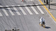 A health worker cycles through an empty street in Shanghai during the city’s ongoing lockdown