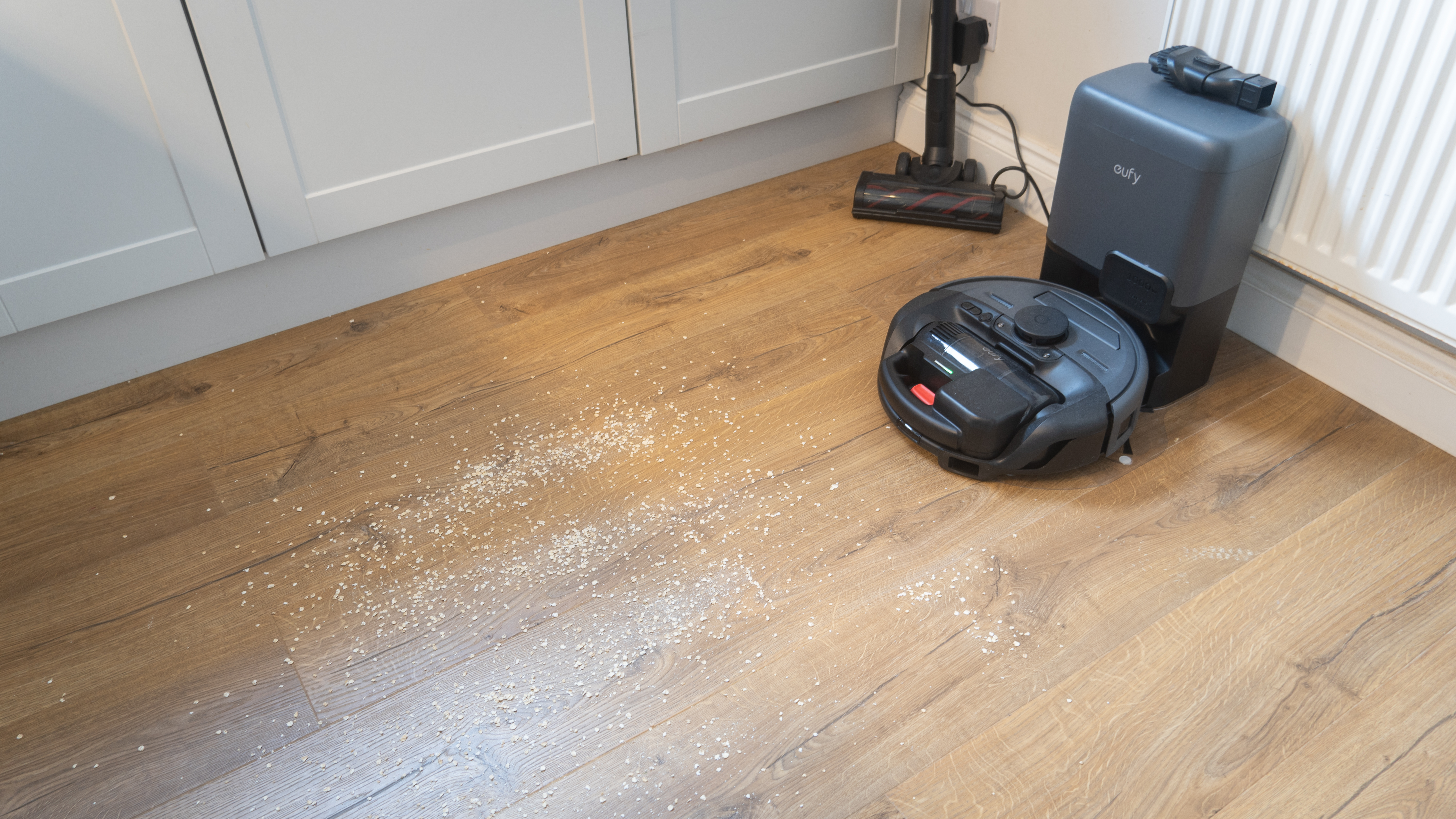 Oats sprinkled on hard floor in front of Eufy E20, ready for suction test