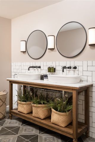 Pale pink bathroom with two sinks and circular mirrors