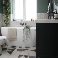 Black and white bathroom with patterned floor tiles and white bath