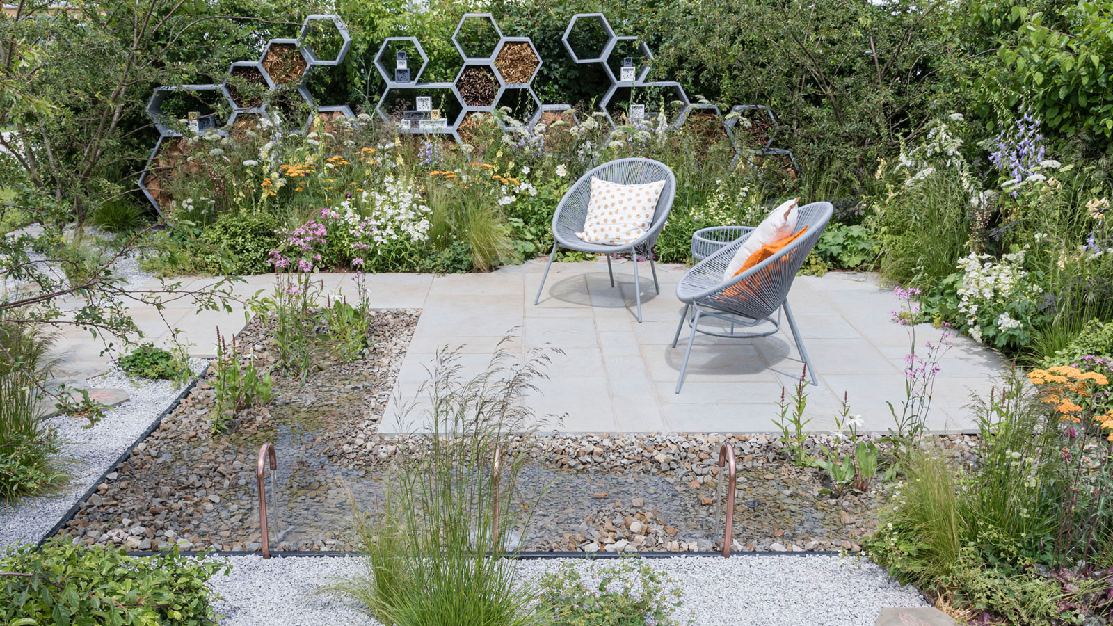 pollinator friendly garden design with pond, insect hotels, white gravel and drought tolerant planting