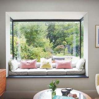 Oriel window seat with comfy cushions and a view to an established garden