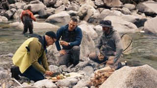 Stanley cooks by a river side with local fishermen