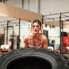 Hybrid training: A woman pushing a tyre at the gym